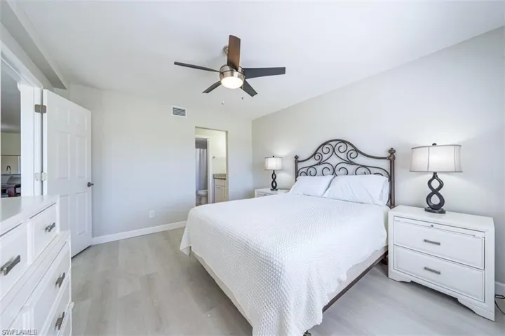 Bedroom featuring light wood-type flooring, a ceiling fan, and ensuite bath