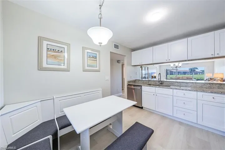 Kitchen with white cabinetry, dishwasher, and light wood-style floors