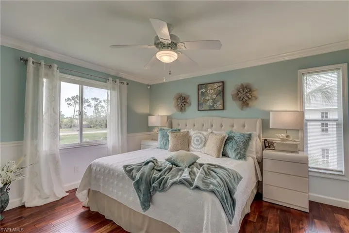 Bedroom featuring ornamental molding, dark wood-style floors, ceiling fan, and multiple windows