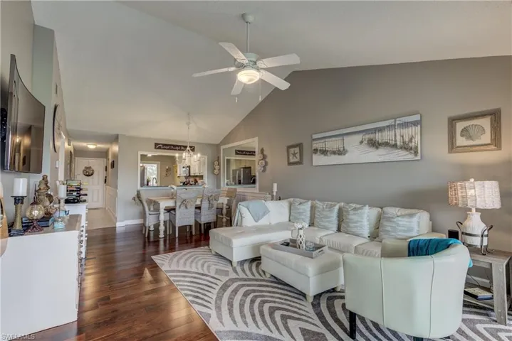 Living area featuring ceiling fan, dark wood-style flooring, and a high ceiling
