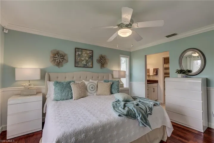 Bedroom with ornamental molding, dark wood-type flooring, connected bathroom, and a ceiling fan