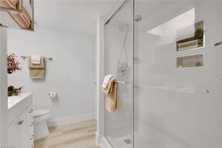 Bathroom with vanity, a stall shower, and light wood-type flooring