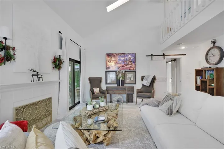 Living room with a barn door, a fireplace, high vaulted ceiling, and a skylight