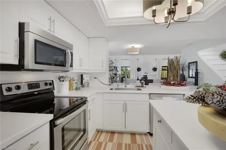 Kitchen with appliances with stainless steel finishes, white cabinetry, a chandelier, a peninsula, and open floor plan