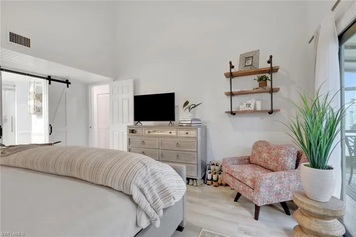 Bedroom on 1st floor with a barn door, light wood-style floors, and ensuite bath