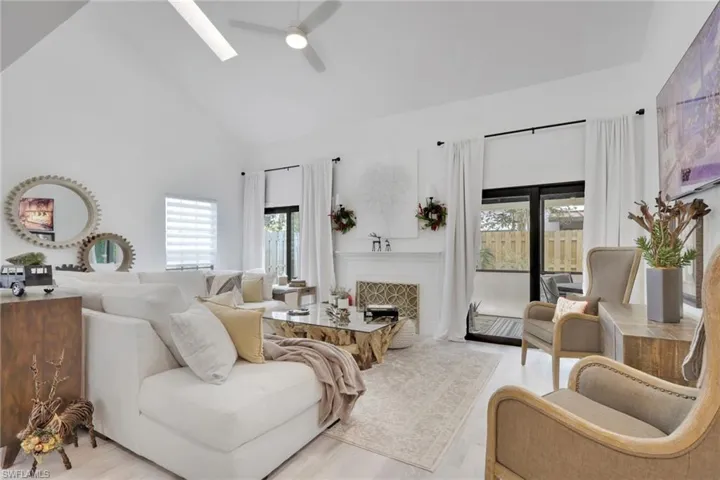 Living area with high vaulted ceiling, a tile fireplace, plenty of natural light, and ceiling fan