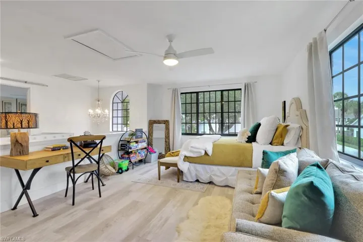 Loft featuring wood finished floors, a ceiling fan, and a chandelier