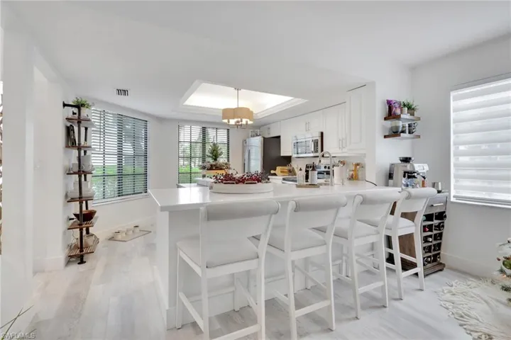 Kitchen with white cabinetry, a breakfast bar, a peninsula, light wood-type flooring, and stainless steel appliances
