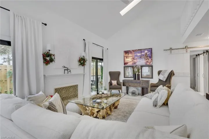 Living area featuring a barn door, a skylight, high vaulted ceiling, and a fireplace