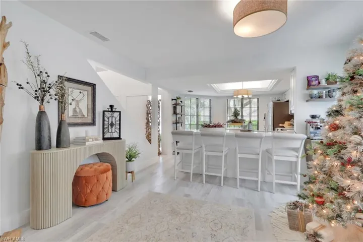 Kitchen with a kitchen breakfast bar, a skylight, light wood finished floors, freestanding refrigerator, and light countertops
