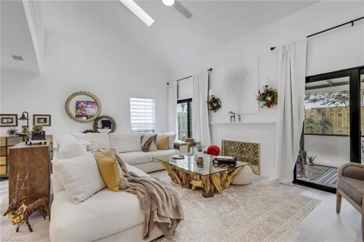 Living area with high vaulted ceiling, wood finished floors, and a fireplace with flush hearth
