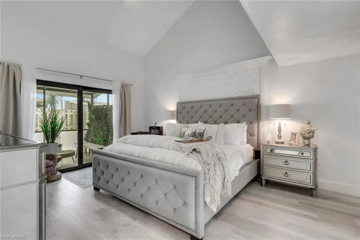 Primary Bedroom on 1st floor with high vaulted ceiling, access to outside, light wood-style flooring, and a ceiling fan