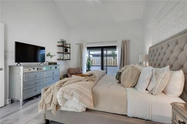 Primary Bedroom on 1st floor with access to exterior, wood finished floors, ceiling fan, and high vaulted ceiling