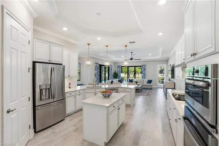 Kitchen featuring a raised ceiling, open floor plan, hanging light fixtures, stainless steel appliances, and recessed lighting