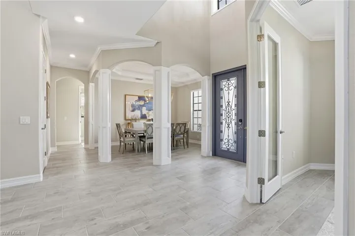 Foyer entrance with ornamental molding, wood tiled floors, and arched walkways