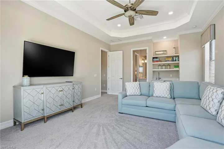 Living room with ornamental molding, a raised ceiling, ceiling fan, carpet floors, and recessed lighting