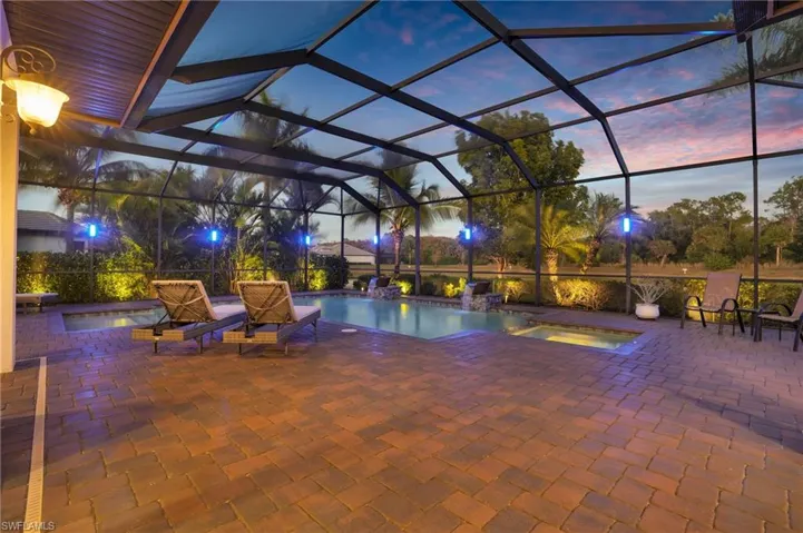 View of pool with glass enclosure, a pool with connected hot tub, a sunroom, and a patio