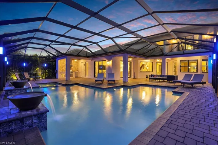 Pool at dusk with a sunroom, glass enclosure, and a patio area