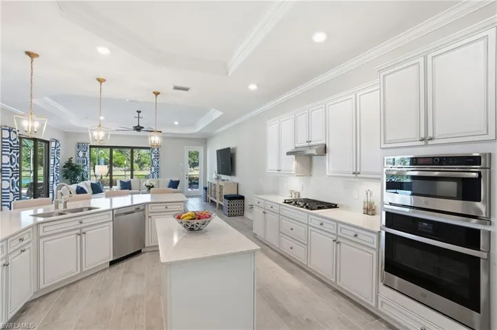 Kitchen featuring stainless steel appliances, open floor plan, white cabinetry, a raised ceiling, and recessed lighting