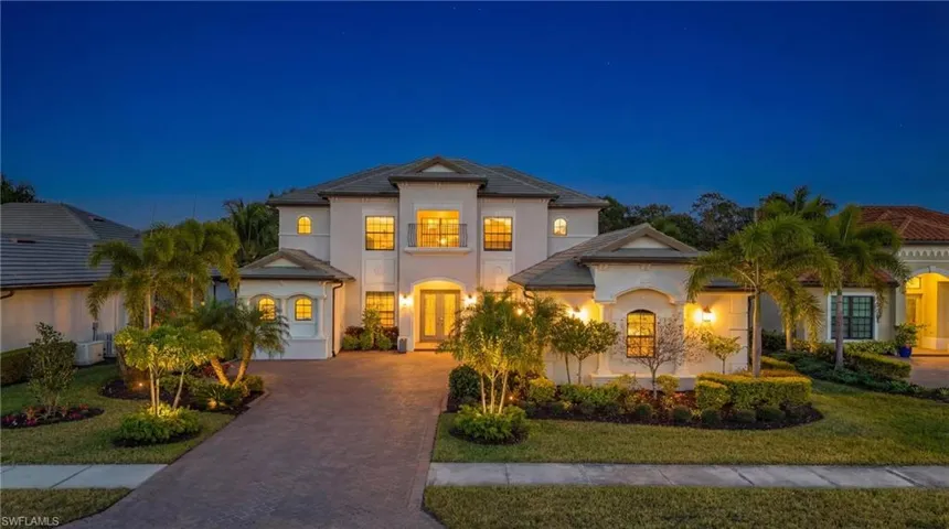View of front facade featuring a front yard, stucco siding, and decorative driveway