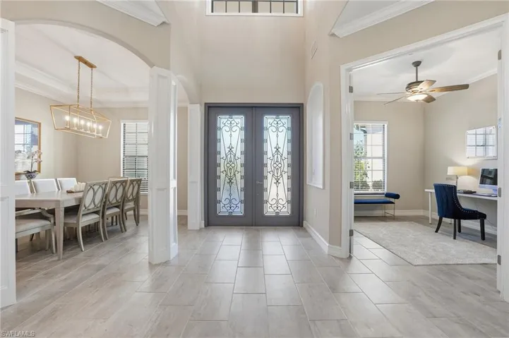 Foyer with crown molding, arched walkways, french doors, a high ceiling, and healthy amount of natural light