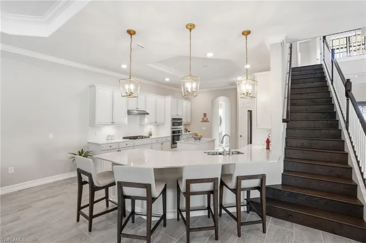Kitchen featuring a tray ceiling, a peninsula, wood finish floors, a breakfast bar area, and hanging light fixtures