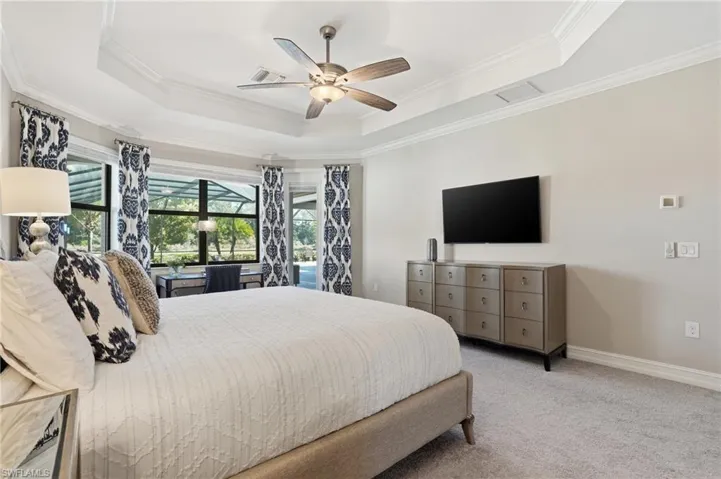 Bedroom featuring ceiling fan, carpet floors, crown molding, and a tray ceiling
