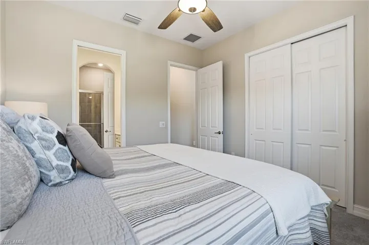 Carpeted bedroom with a ceiling fan, ensuite bathroom, and a closet