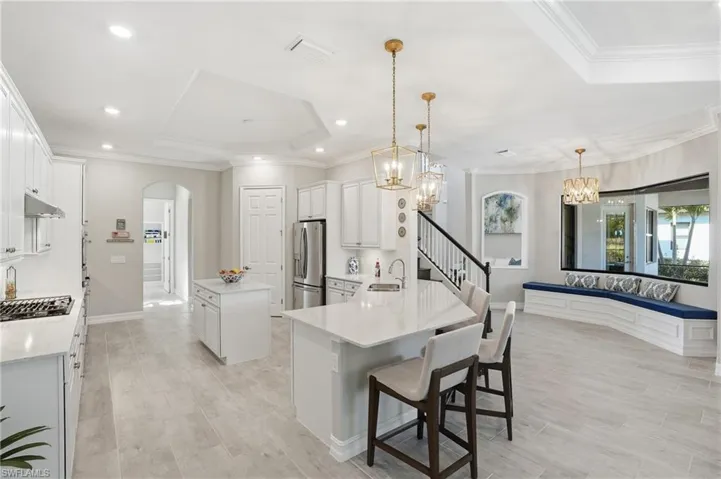 Kitchen featuring crown molding, white cabinets, pendant lighting, arched walkways, and a center island