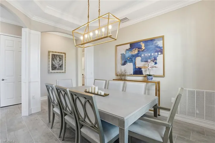 Dining area with ornamental molding, arched walkways, and a chandelier