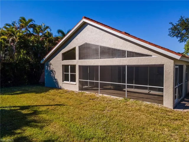 Rear view of property featuring stucco siding, a lawn, and a sunroom