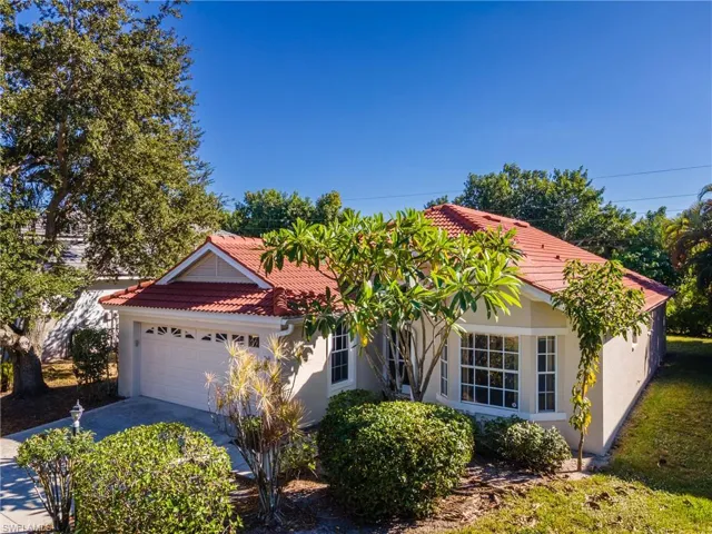 Ranch-style home with an attached garage, a tile roof, stucco siding, and driveway