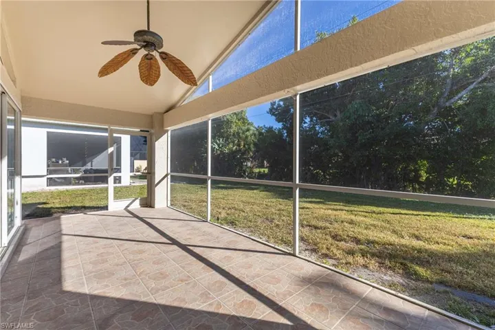Unfurnished sunroom featuring a ceiling fan, lofted ceiling, and a patio area