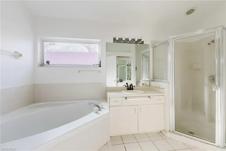 Bathroom featuring a shower stall, vanity, light tile patterned floors, and a bath