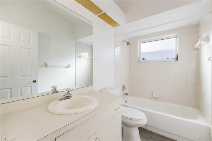 Bathroom featuring vanity, washtub / shower combination, and wood finished floors
