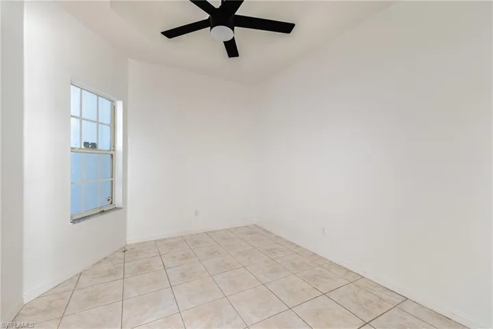 Empty room with ceiling fan and light tile patterned floors