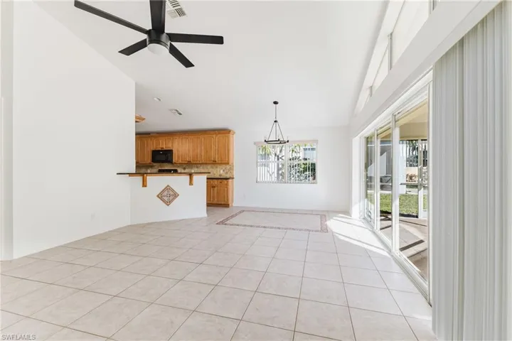 Unfurnished living room with light tile patterned floors, lofted ceiling, a ceiling fan, and a chandelier