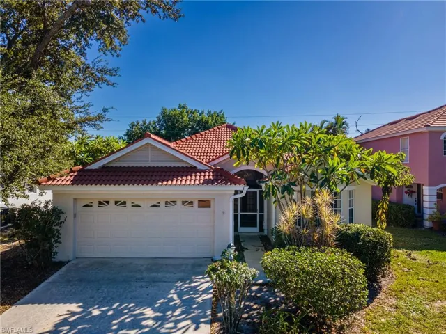 View of front facade with a garage, driveway, stucco siding, and a tile roof