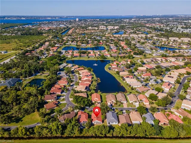 Aerial view of property and surrounding area featuring nearby suburban area and a nearby body of water
