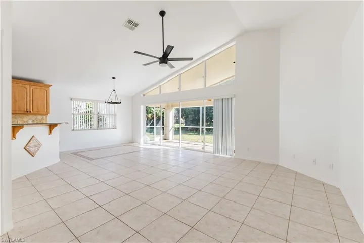 Unfurnished living room featuring light tile patterned floors, vaulted ceiling, and ceiling fan