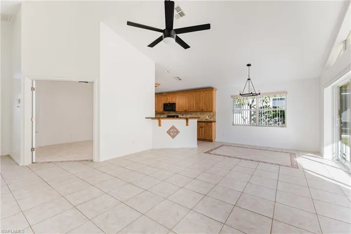 Unfurnished living room with a ceiling fan, light tile patterned flooring, lofted ceiling, and hanging lights