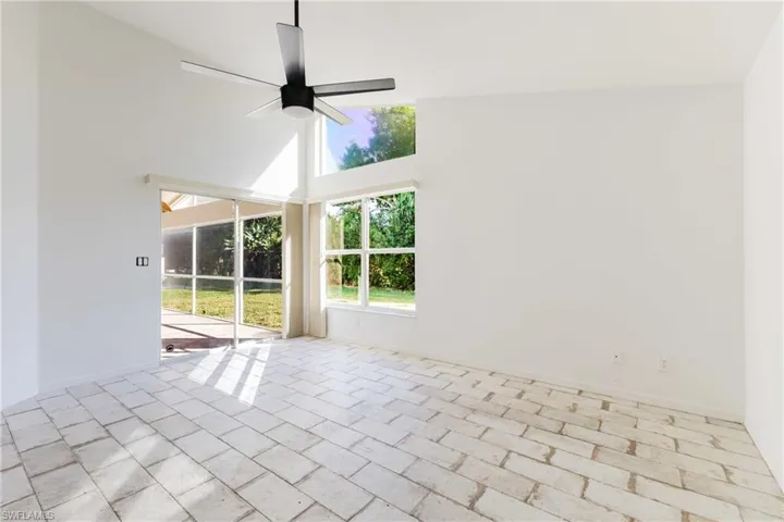 Unfurnished room featuring a sunroom, a ceiling fan, and lofted ceiling