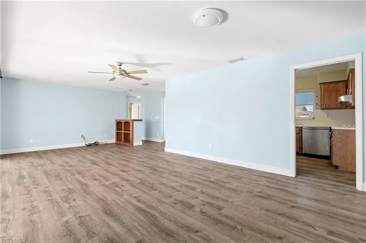 Unfurnished living room featuring a ceiling fan, baseboards, visible vents, and wood finished floors