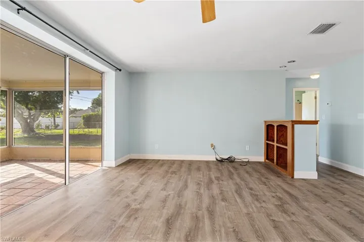 Empty room featuring ceiling fan, baseboards, visible vents, and wood finished floors