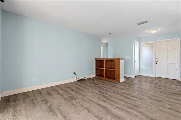 Empty room featuring baseboards, wood finished floors, and visible vents