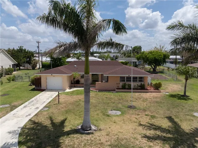 Ranch-style home featuring an attached garage, a front lawn, fence, and concrete driveway