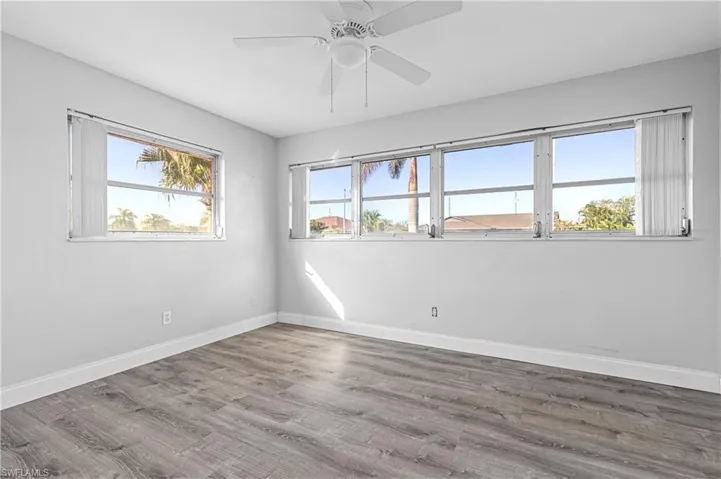 Unfurnished room featuring a ceiling fan, baseboards, and wood finished floors