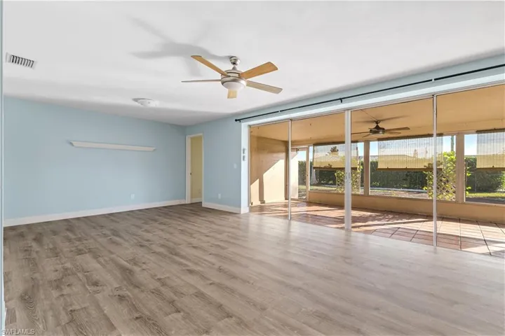 Unfurnished living room with baseboards, a ceiling fan, wood finished floors, and visible vents