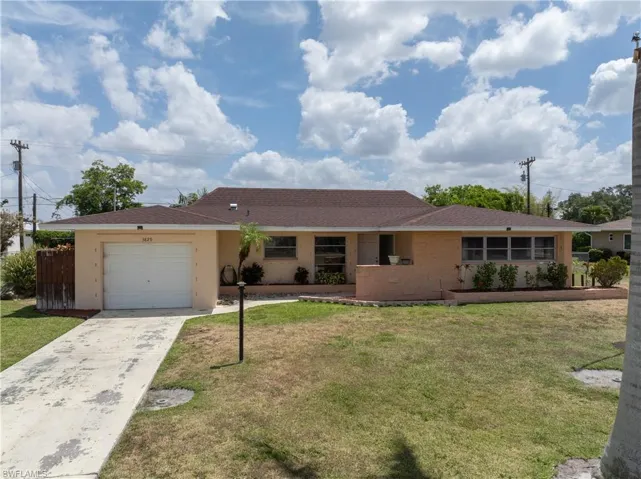 Ranch-style house featuring an attached garage, driveway, and a front lawn