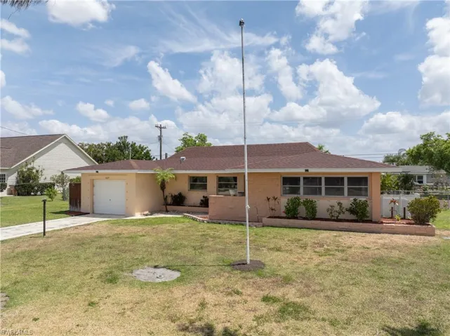 Ranch-style house featuring a front lawn, fence, stucco siding, concrete driveway, and an attached garage